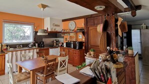 A kitchen with wooden cabinets, a dining table, and chairs. There is a clock on the wall and a window with blinds. - Beautiful home in Vias (Vias)
