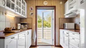 A kitchen with white cabinets, a coffee maker, a microwave, and a view through a glass door to the outside. - Beautiful home in Tarm with WiFi (Tarm)