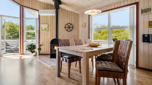 A modern interior with a wooden ceiling, large windows, a fireplace, and a dining area with wicker chairs. - Beautiful home in Tarm with WiFi (Tarm)