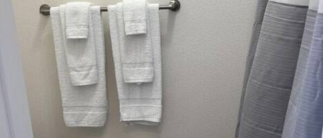 A small bathroom with a toilet, two towels hanging on a metal rack, and a shower curtain.