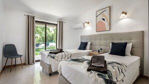 A modern hotel room with two beds, a chair, and a view of the outdoors. - Wonderful private villa for 8 people with A/C, WIFI, private pool, TV and terrace (Albufeira)