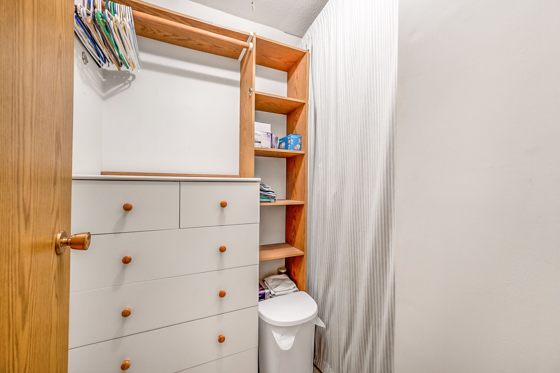 Une petite salle de bain avec un meuble-lavabo en bois, des toilettes et une petite étagère contenant des articles de toilette.