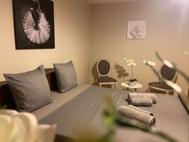 Habitación de hotel con una cama grande, dos sillas, una mesita y una orquídea en maceta.