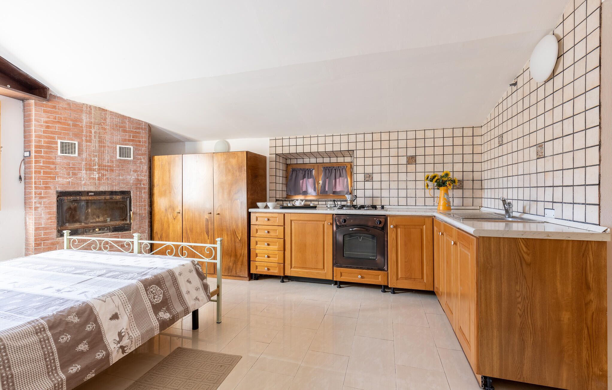 A compact kitchen with wooden cabinets, a built-in oven, and a tiled backsplash.
