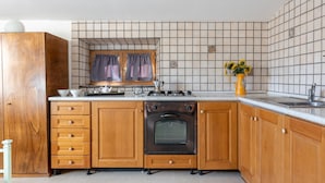 Een keuken met houten kastjes, een fornuis en een betegelde spatwand.