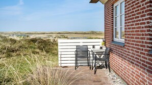 A patio with a table and chairs, a brick wall, and a view of a water body and landscape. - Awesome home in Nørre Nebel (Nørre Nebel)