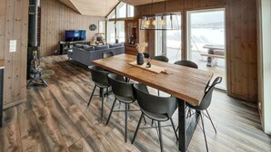 Una cocina moderna con una mesa y sillas de madera, estufa empotrada y un ventanal con vistas al exterior.
