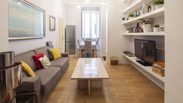 A modern living room with a sofa, coffee table, TV, and shelves with plants. - Nice apartment for 9 guests with A/C, WIFI and TV (Rome)