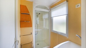 Ein Badezimmer mit Dusche, Toilette und Fenster.