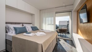 A modern hotel room with a large bed, a balcony with a chair, and a TV mounted on the wall. - Nice home in Novalja with sauna (Novalja)