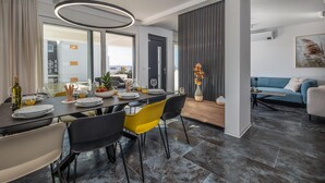 A modern dining area with a dark wooden table, yellow chairs, and a large circular light fixture. - Nice home in Novalja with sauna (Novalja)