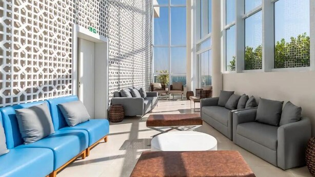A modern interior with a blue sofa, grey sofas, and a white coffee table.