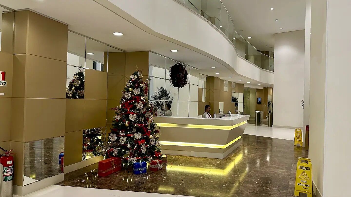 Eine moderne Hotelhalle mit einer Rezeption, Weihnachtsdekorationen und einem Feuerlöscher.