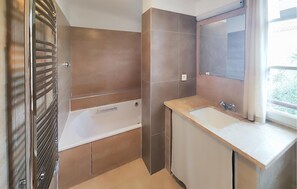 Bathroom features a large bathtub, separate shower area, and vanity with sink.