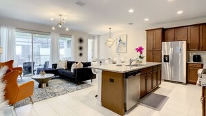 A modern kitchen with a central island, stainless steel appliances, and a dining area with a sofa and chairs.