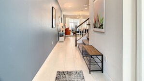 A modern hallway with a staircase, a bench, and artwork on the walls.