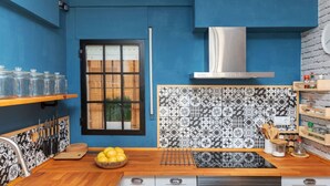 Una cucina moderna con pareti blu, zoccolo a contrasto bianco e nero e pensili in legno, oltre a una cappa aspirante in acciaio inossidabile.
