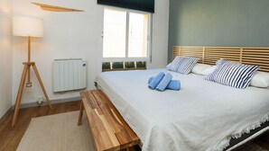 Camera da letto con un letto, testiera in legno, lampada da comodino, finestra, termosifone e una panca in legno.