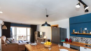 Una cucina moderna con isola in legno, zona pranzo con divano e un'ampia finestra.