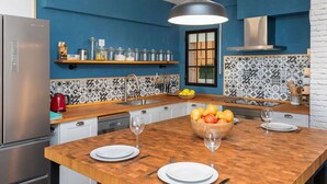 Una cucina moderna con pareti blu, un piano di lavoro in legno e un backsplash a motivi bianchi e neri. Si notano due lavelli, un frigorifero e una macchina da caffè.