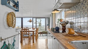 Una cocina moderna con una mesa de comedor de madera, un ventanal con vistas y una encimera con hogaza de pan.