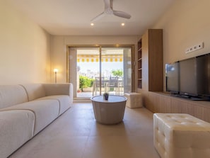 A modern living room with a sofa, a coffee table, a TV, and a ceiling fan.