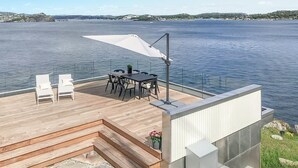 A deck with a table and chairs, overlooking a body of water. - Stunning home in Stabbestad (Stabbestad)