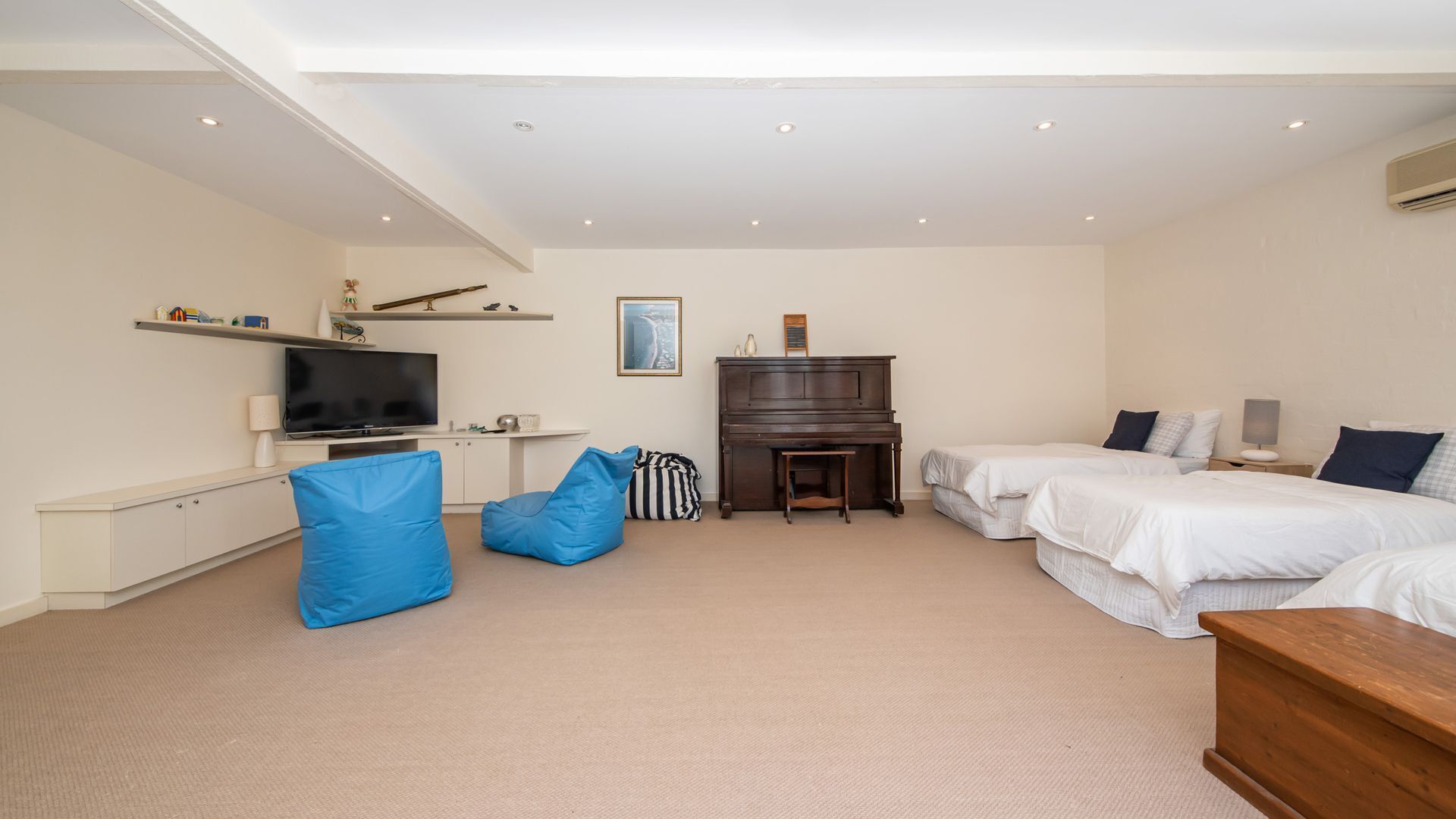 A bedroom with two beds, a TV, a piano, and a desk.