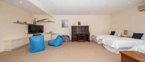 A bedroom with two beds, a TV, a piano, and a desk.