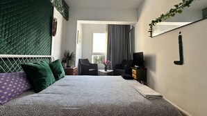Ein Schlafzimmer mit Bett, Sessel, Fernseher und Nachttisch.