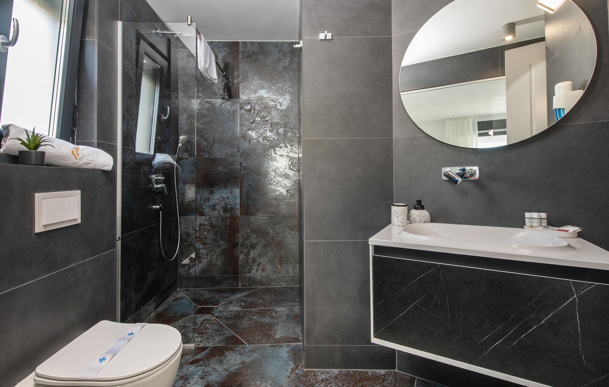 Een moderne badkamer met een inloopdouche, toilet en een wastafelmeubel met een wastafel.