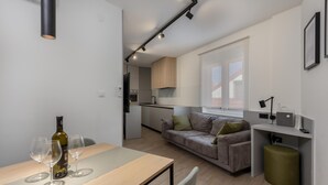 Un espace de vie moderne et compact comprenant un coin repas, un canapé et une kitchenette.