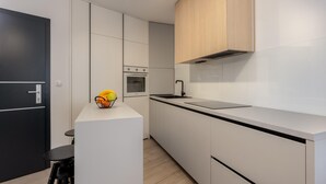 Une cuisine moderne avec des meubles blancs, un plan de travail noir et un petit îlot central agrémenté de fruits.