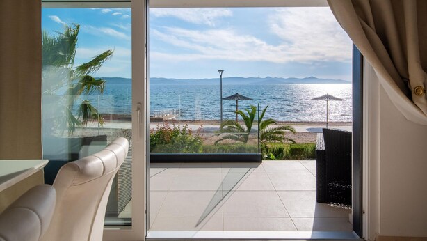 A balcony with a view of the sea, a chair, and a table.