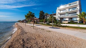 A beachside property with a modern two-story building, a sandy beach, and umbrellas.