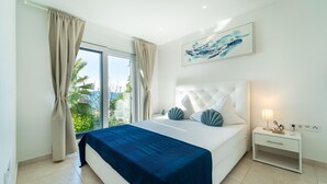 A bedroom with a large bed, a nightstand, a lamp, and a painting on the wall.