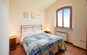 Cozy retreat with a large bed, bedside tables, and a window with wooden shutters.