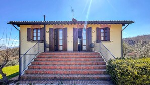 A two-story building with a yellow facade, wooden shutters, and a tiled roof. - 1 bedroom awesome apartment in Gubbio (Gubbio)