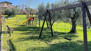 A playground with a slide and swings, surrounded by grass and trees. - 1 bedroom awesome apartment in Gubbio (Gubbio)
