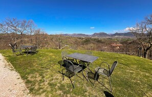 Enjoy a serene outdoor seating area with a table and chairs, offering breathtaking views of the valley and surrounding mountains.