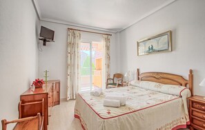 A bedroom with a bed, a desk, a chair, a television, and a painting on the wall. - Awesome home in Santa Pola with WiFi (Santa Pola)