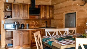 Interior de una cabaña de madera con cocina, una mesa de comedor y un refrigerador.
