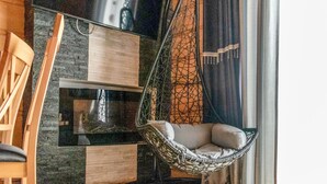 Un interior moderno con una silla colgante, muebles de madera y vistas a través de una ventana.