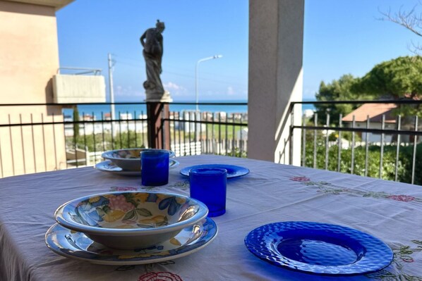 A table set outdoors with a view of the sea and a statue in the background.