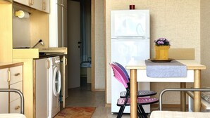A compact kitchen with a washing machine, a refrigerator, and a dining area with a table and chairs. - SE068 - Senigallia, two-room apartment on the sea at the Piramidi residence (Senigallia)