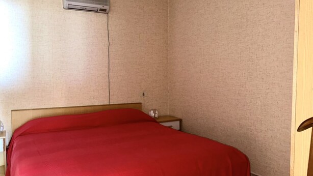 A room with a bed, a nightstand, a wall-mounted air conditioner, and a door. - SE068 - Senigallia, two-room apartment on the sea at the Piramidi residence (Senigallia)
