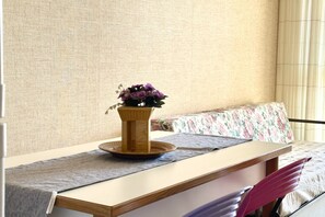 A room with a wooden table, a potted plant, a floral bedspread, and a window with curtains. - SE068 - Senigallia, two-room apartment on the sea at the Piramidi residence (Senigallia)