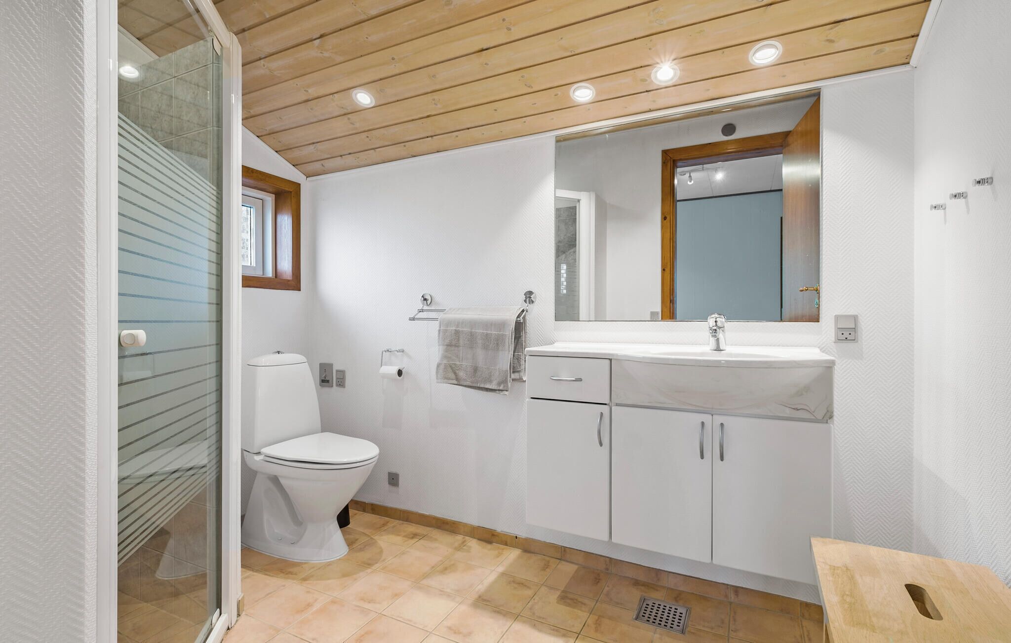 A modern bathroom with a toilet, sink, and mirror.