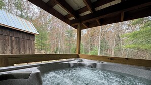 Un bain à remous avec une terrasse en bois et une vue sur une zone boisée.