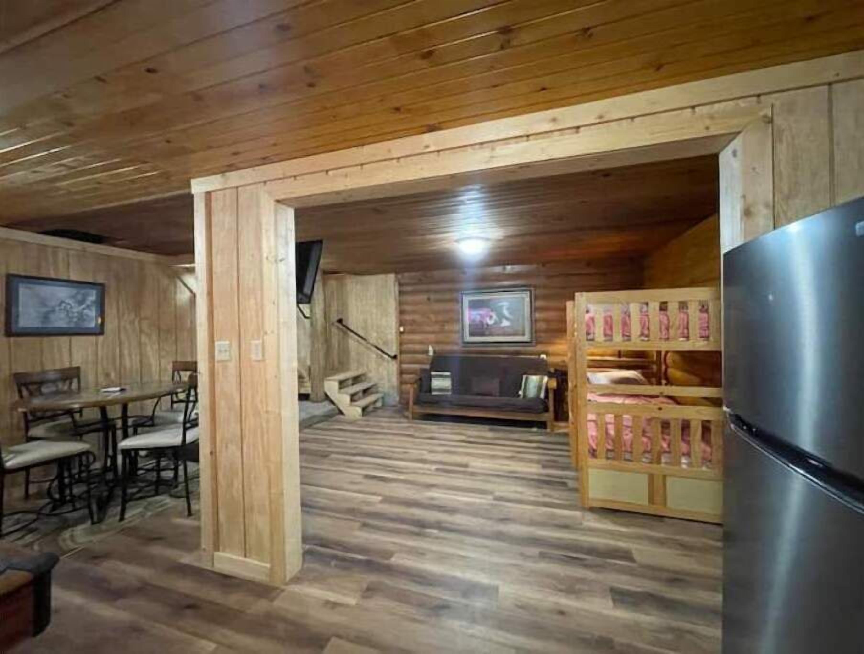 Ein Holzinterieur mit Essbereich, einer Couch, einem Fernseher und einem Kühlschrank.